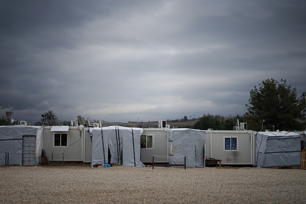 white and gray camper trailer on green grass field under gray cloudy sky during daytime