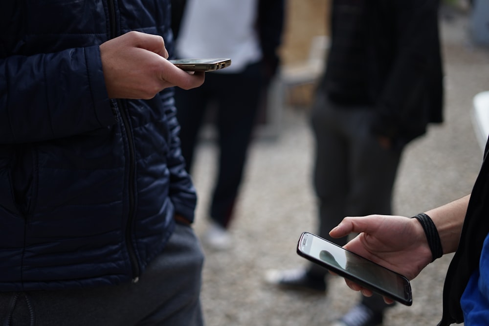 person in black jacket holding white smartphone