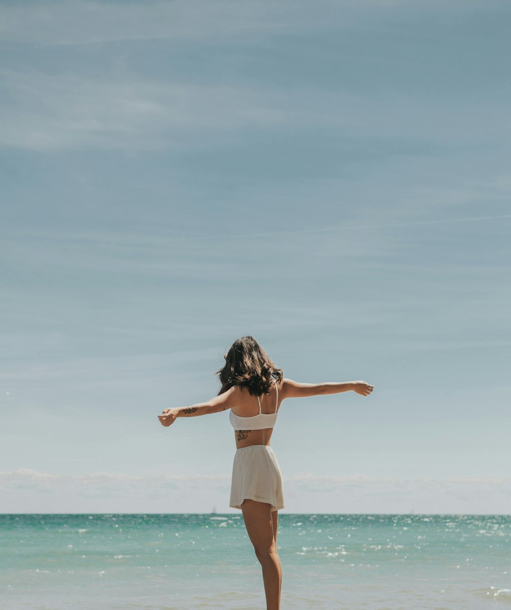 mulher em shorts brancos em pé na praia durante o dia