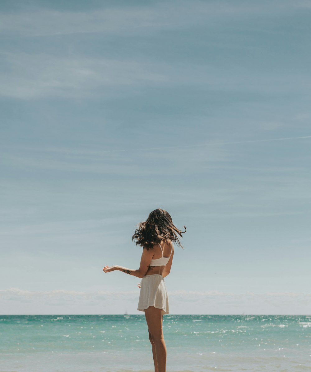 woman in white dress standing on seashore during daytime