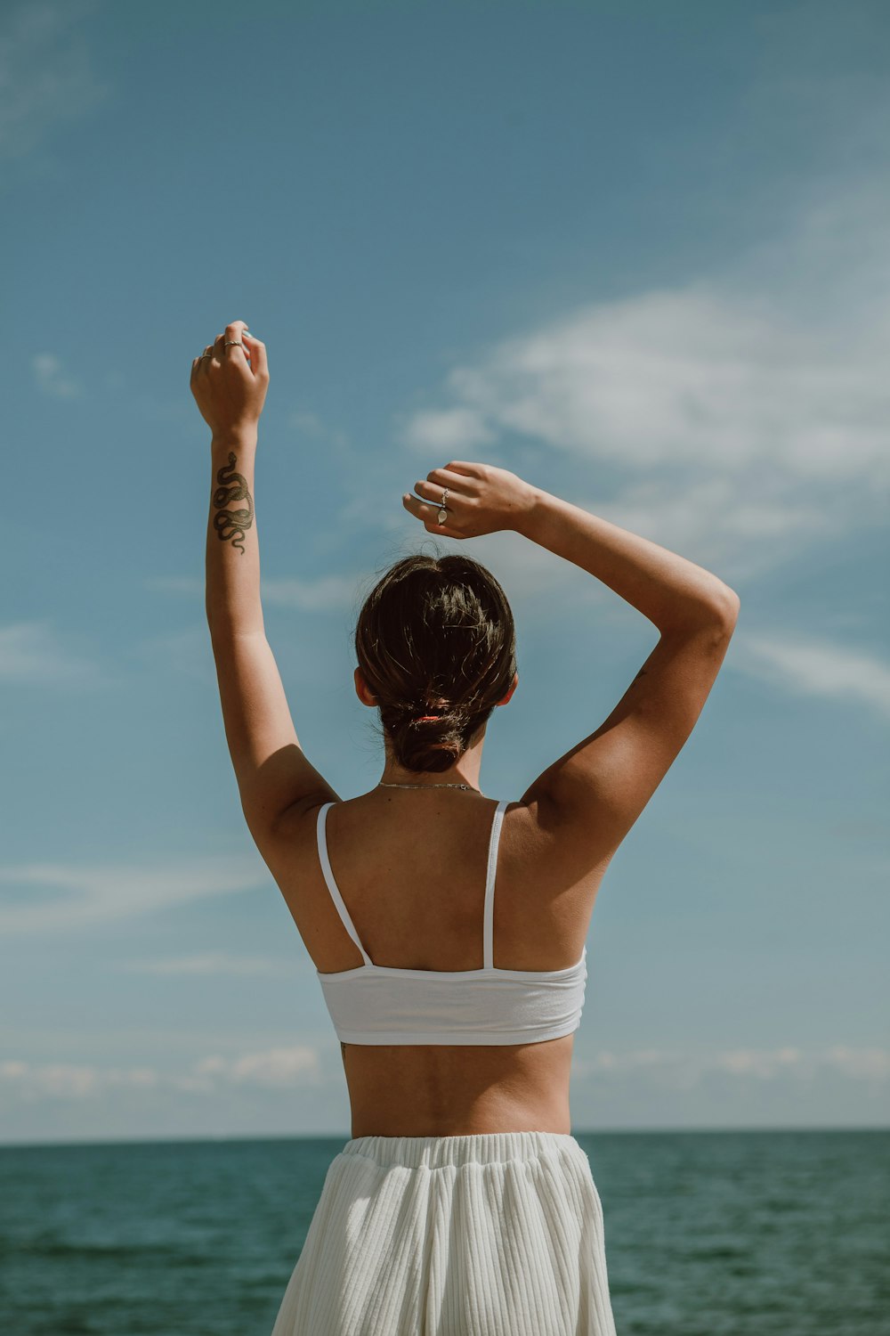 woman in white bikini top raising her hands