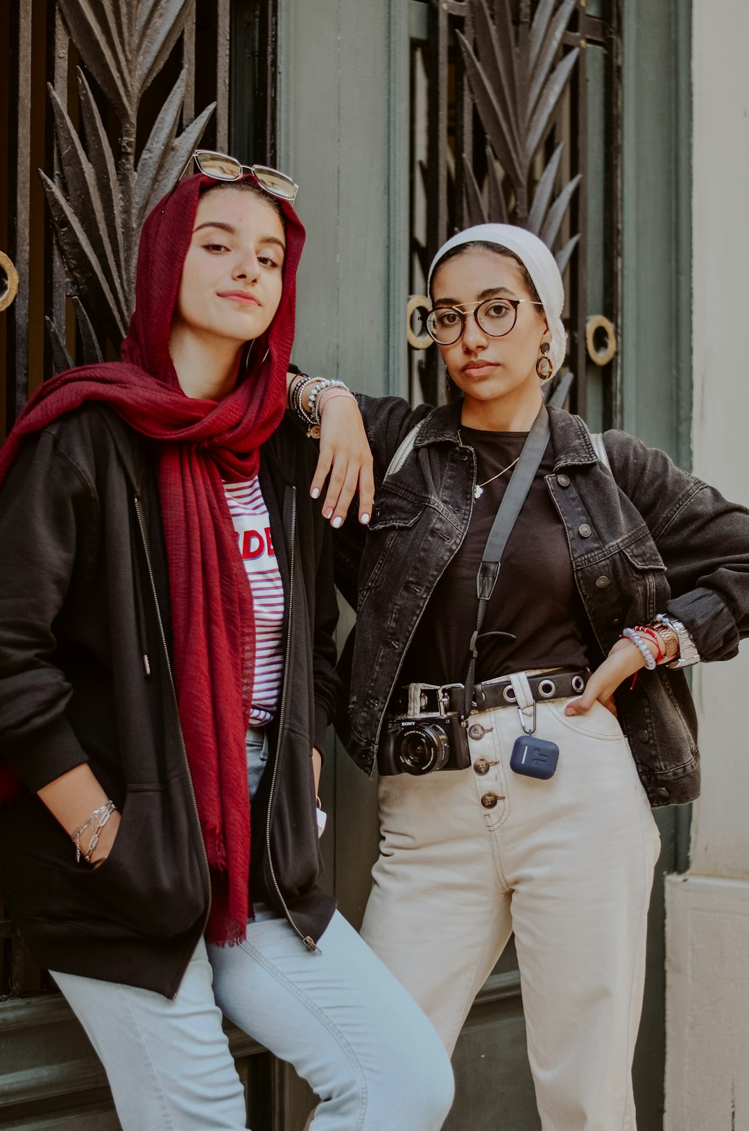 woman in black leather jacket standing beside woman in red hijab