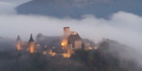 An ancient castle towering over a misty valley under a twilight sky.
