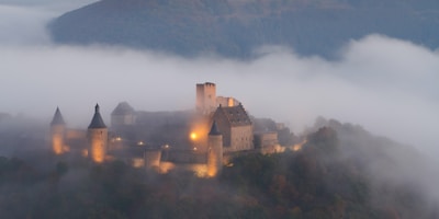 An enchanted castle surrounded by swirling mist and floating lights.