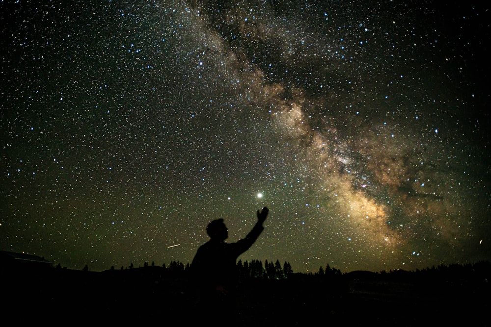 silhouette of man standing under starry night