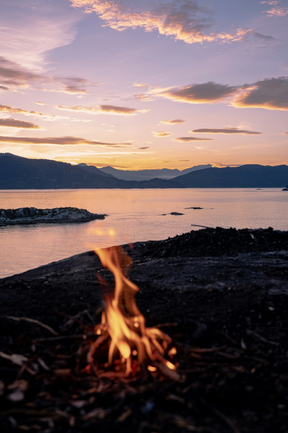 brown and black sand near body of water during sunset