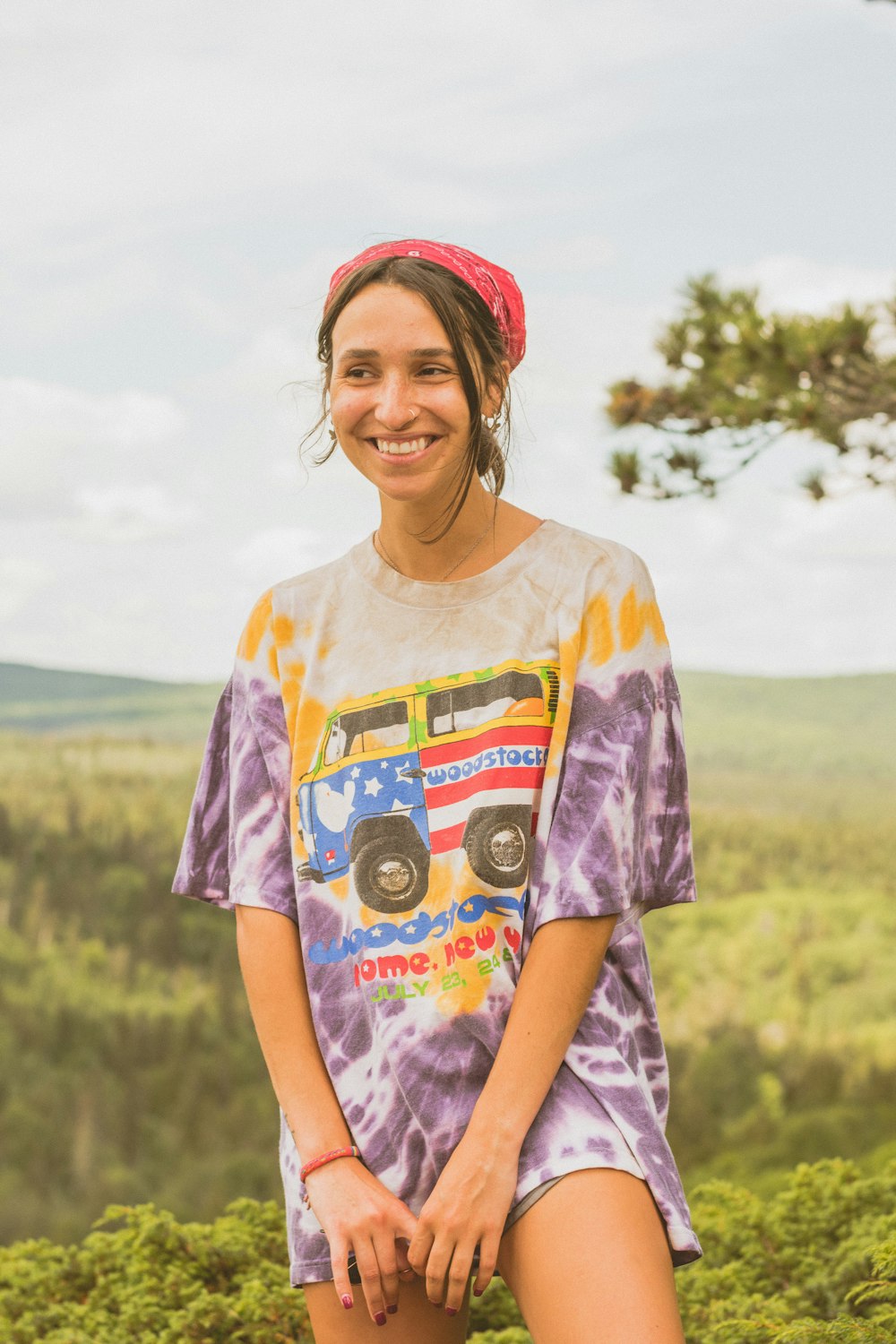 smiling woman in purple and white crew neck t-shirt standing on green grass field during