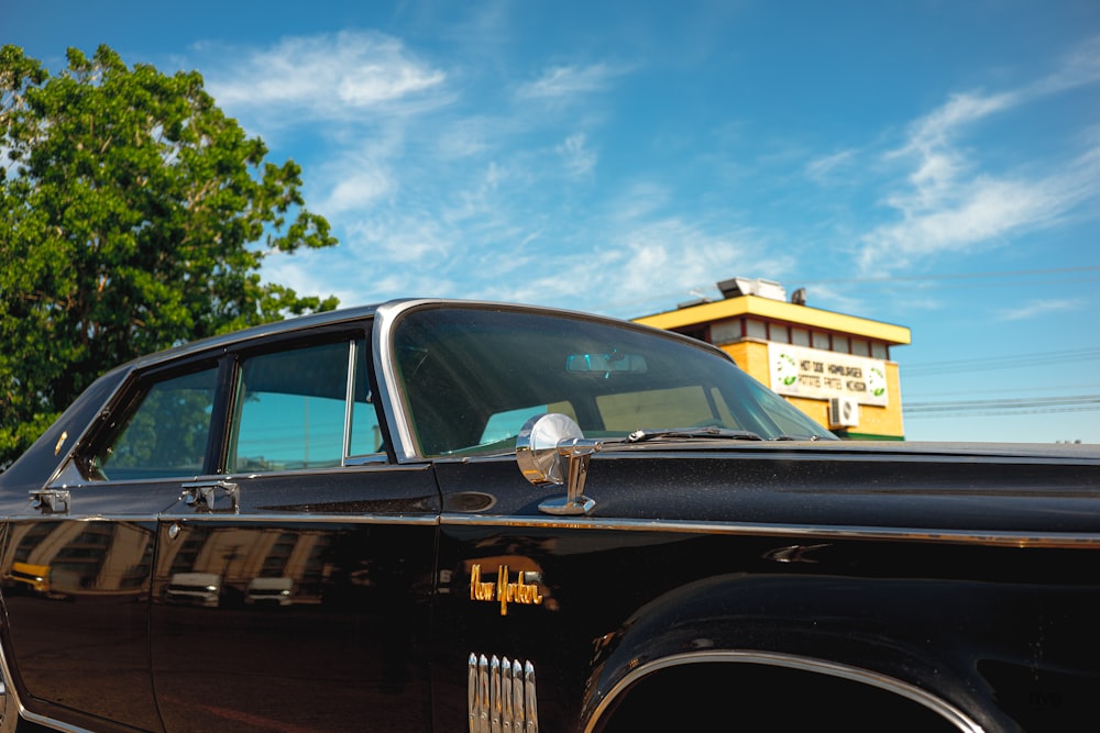 black sedan parked near green tree during daytime