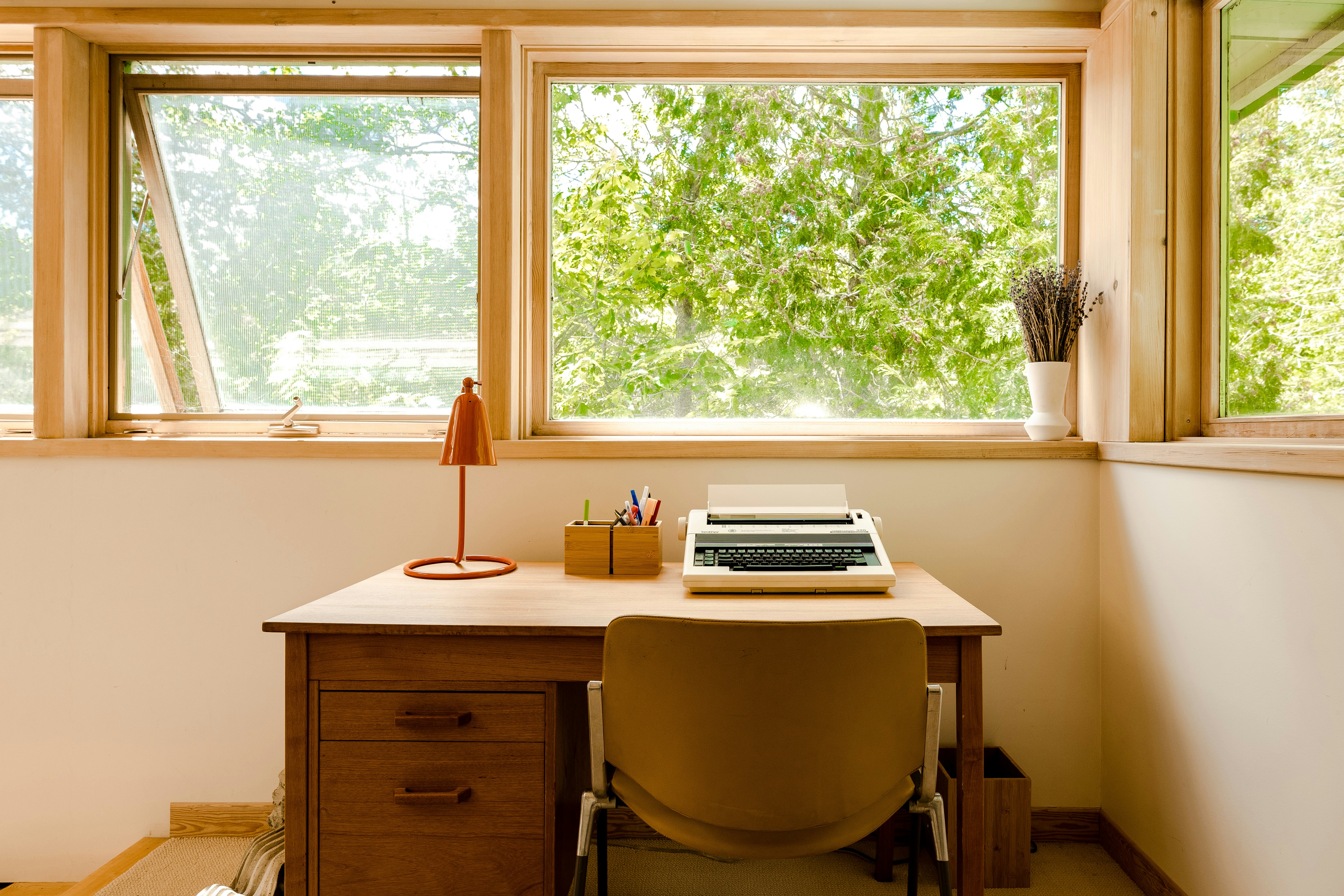 A person writing at a sunlit desk.
