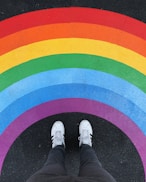 person in white pants and white sneakers standing on black and red carpet