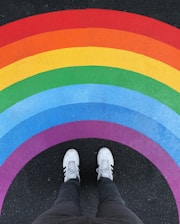 person in white pants and white sneakers standing on black and red carpet