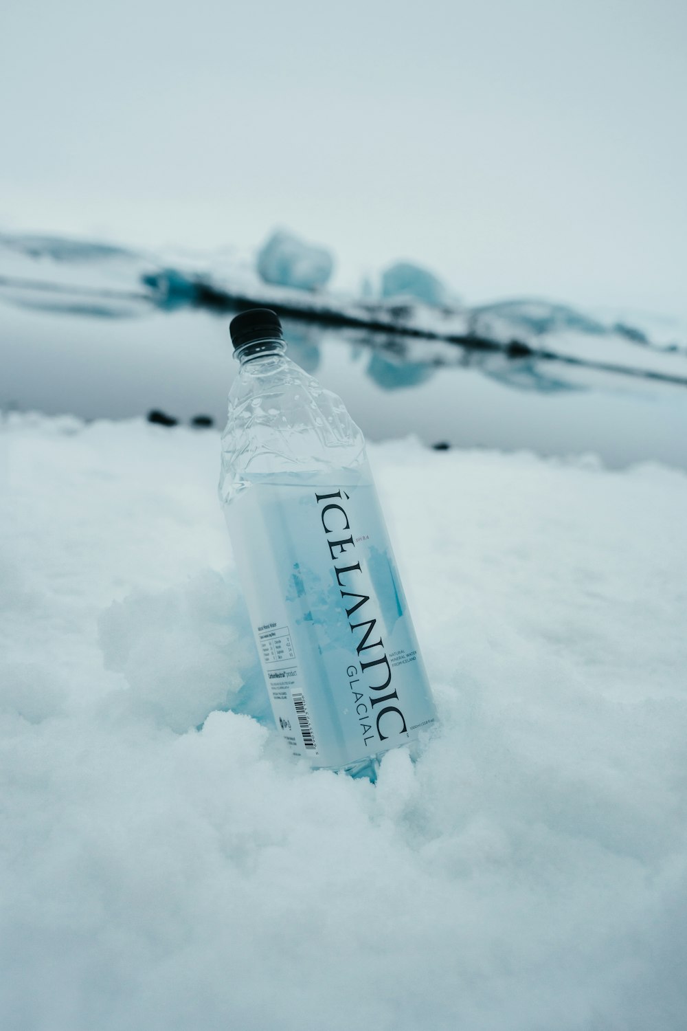 garrafa de vidro transparente no chão coberto de neve