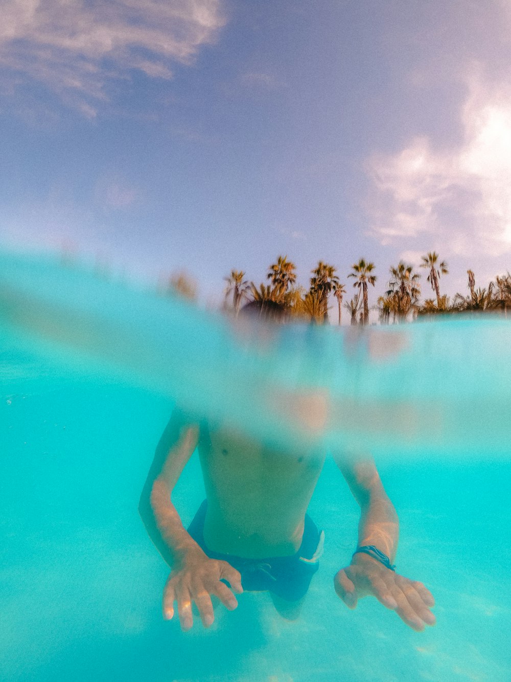 man in blue shorts swimming on pool during daytime