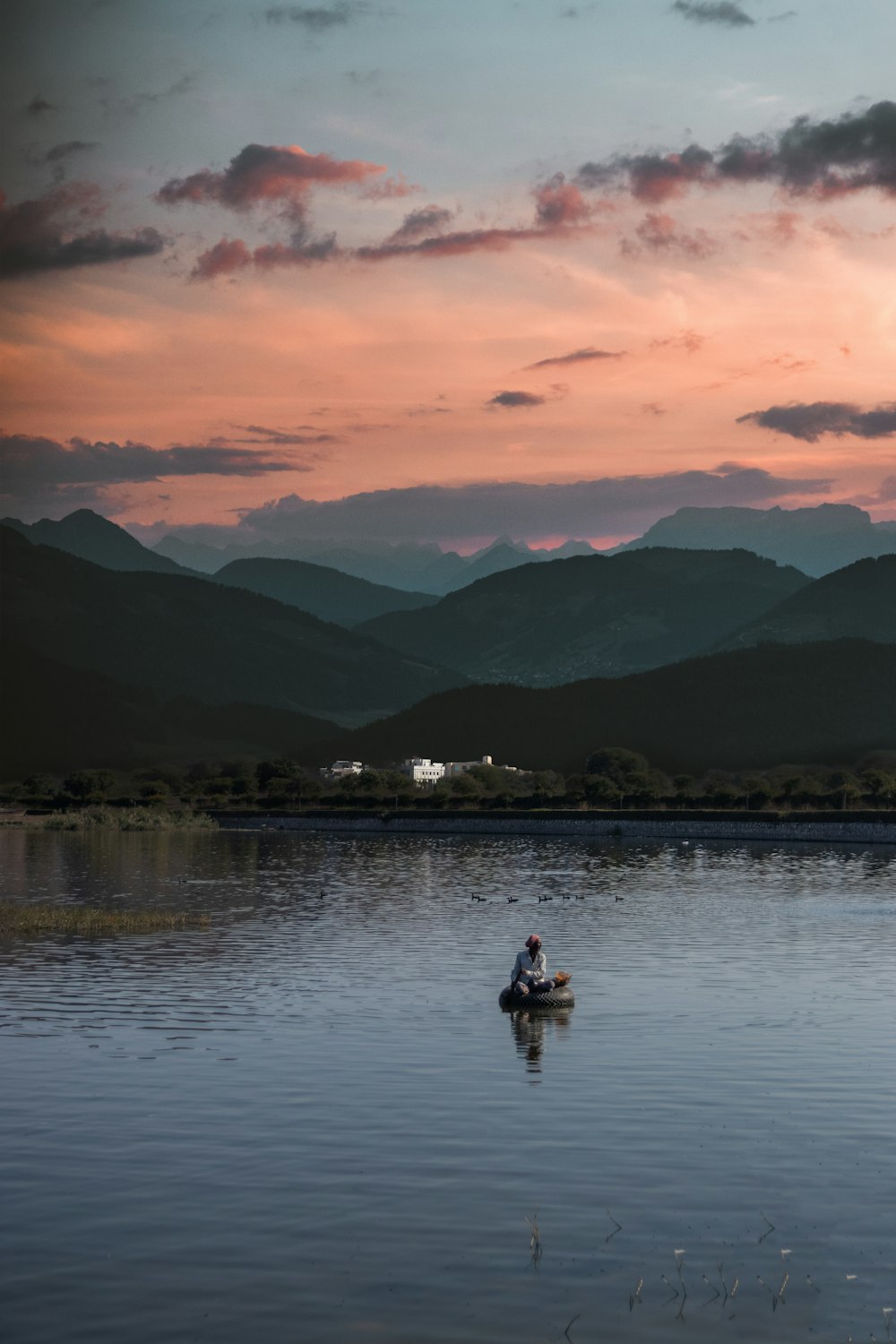 2 people on lake during sunset