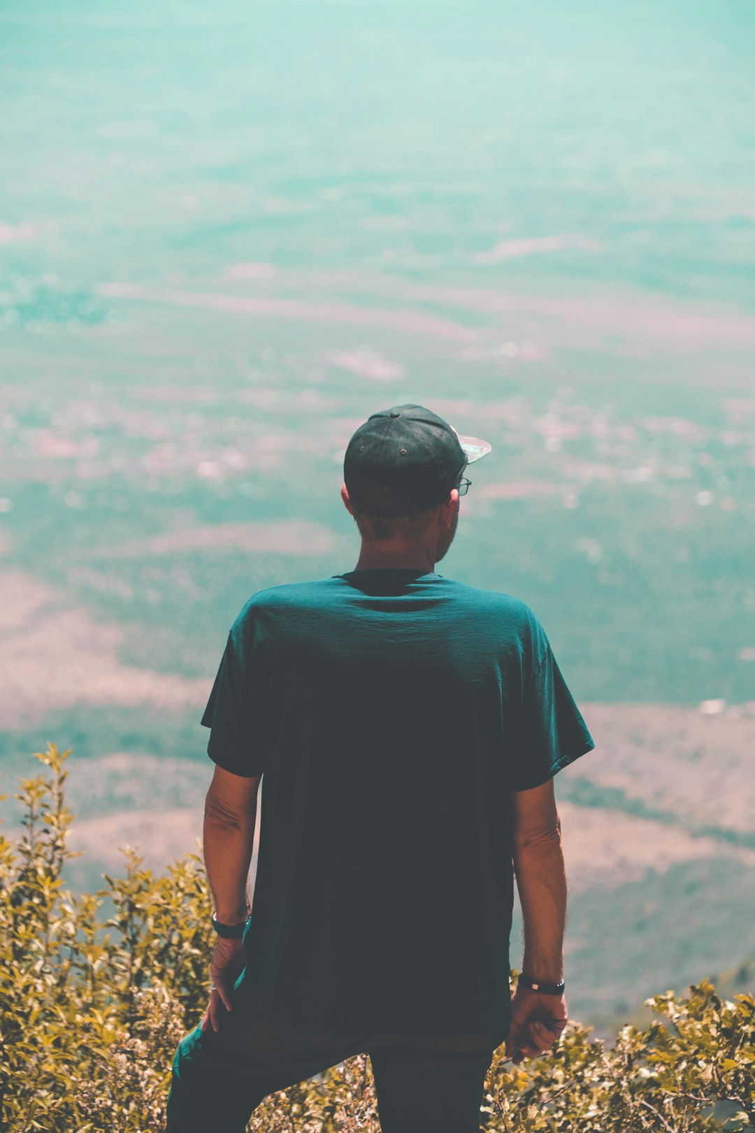 man in blue crew neck t-shirt standing near yellow flowers during daytime