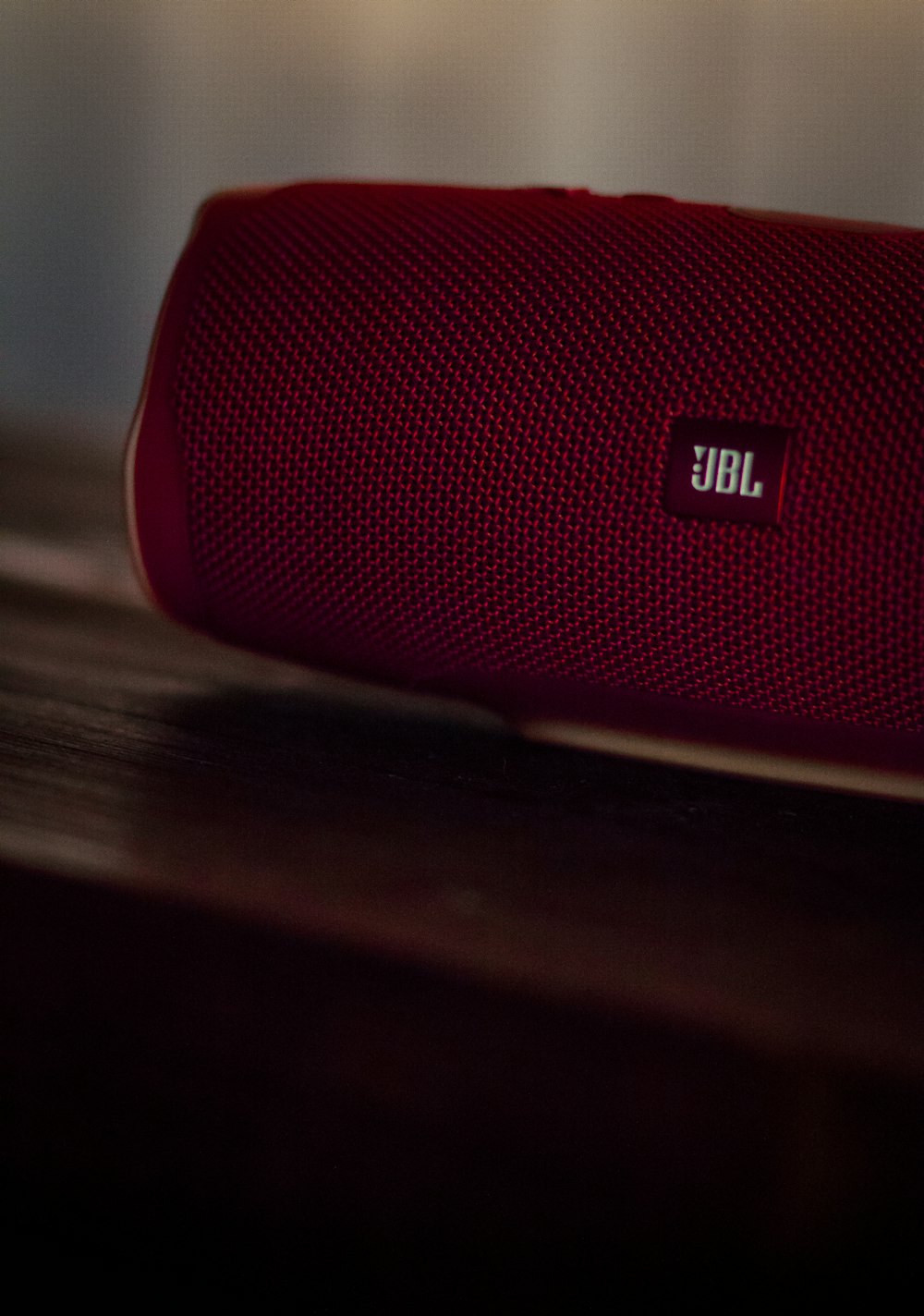 red jbl portable speaker on brown wooden table