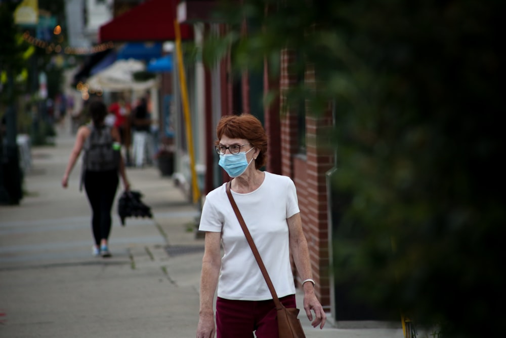 woman in white crew neck t-shirt and red pants standing on sidewalk during daytime