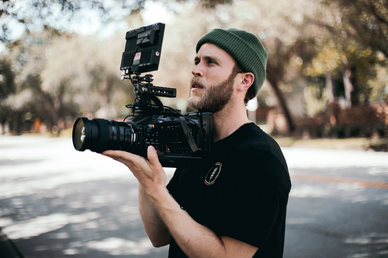A videographer outdoors holding a cinema camera rig