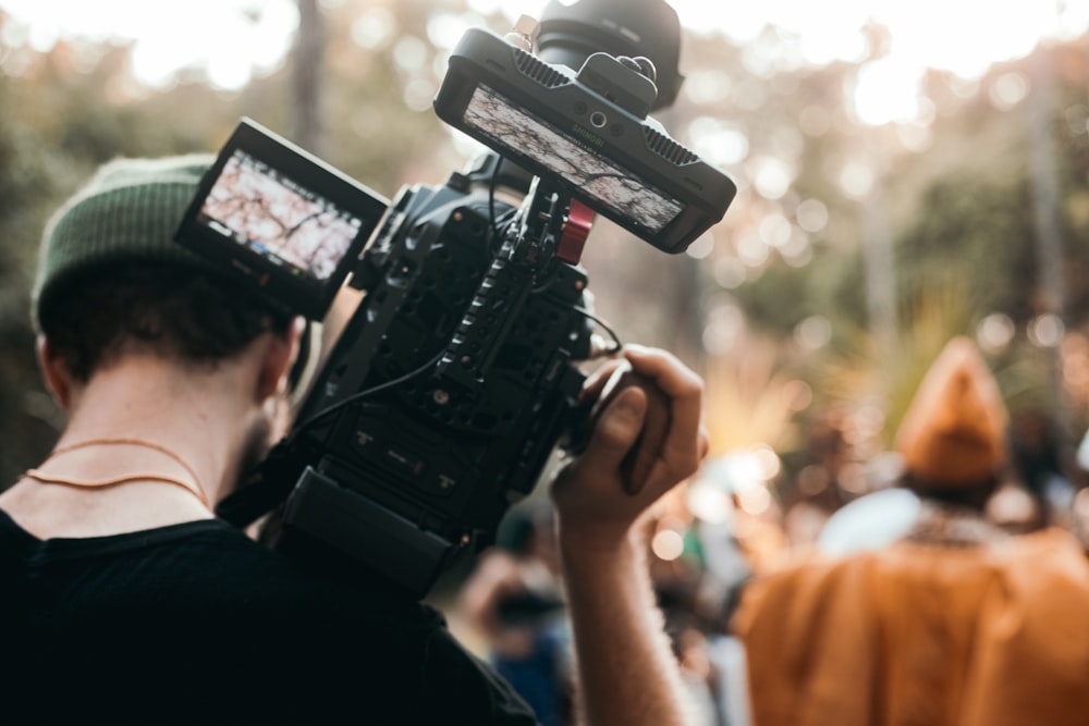 person holding black dslr camera taking photo of people during daytime