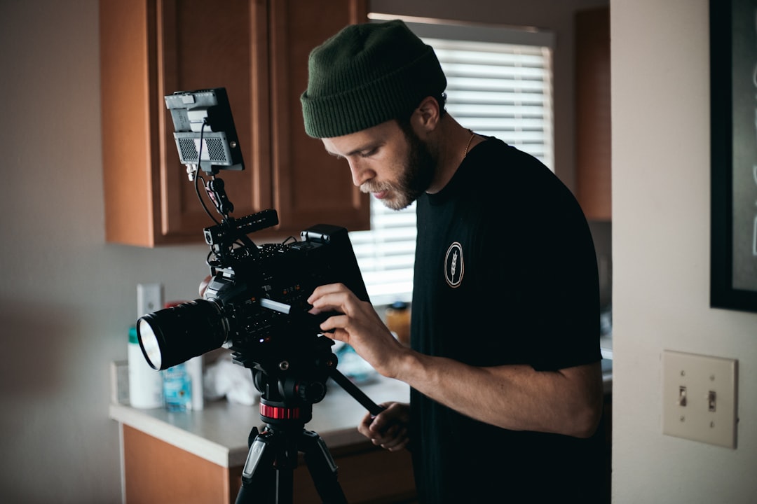 man in black crew neck t-shirt holding black dslr camera,