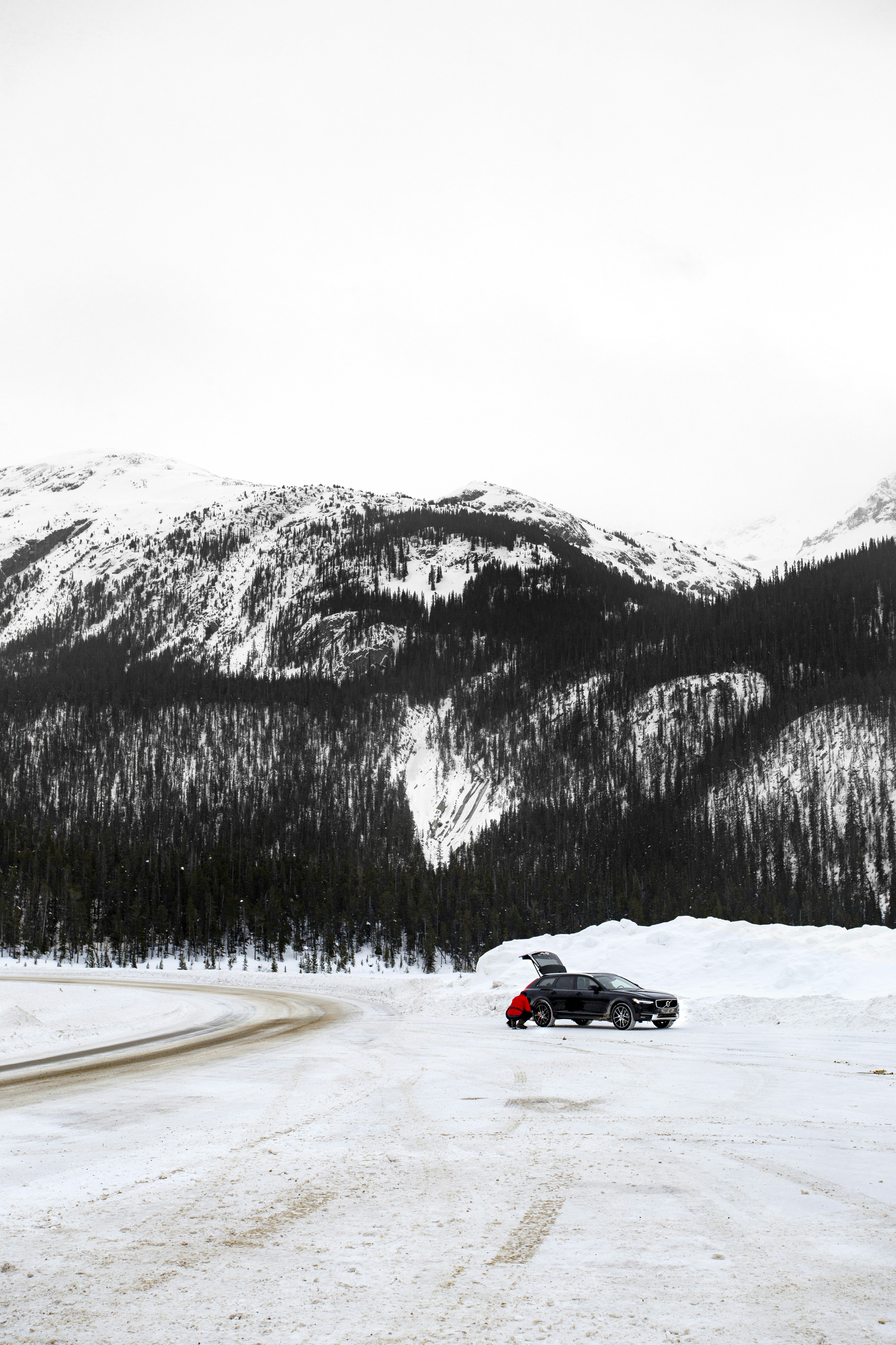 voiture de sport noire et rouge sur une route enneigée près d’une montagne enneigée pendant la journée
