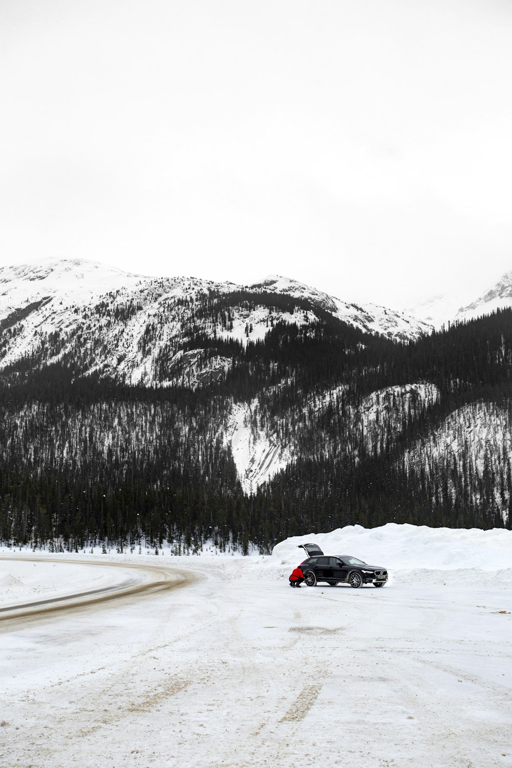 black and red sports car on snow covered road near snow covered mountain during daytime