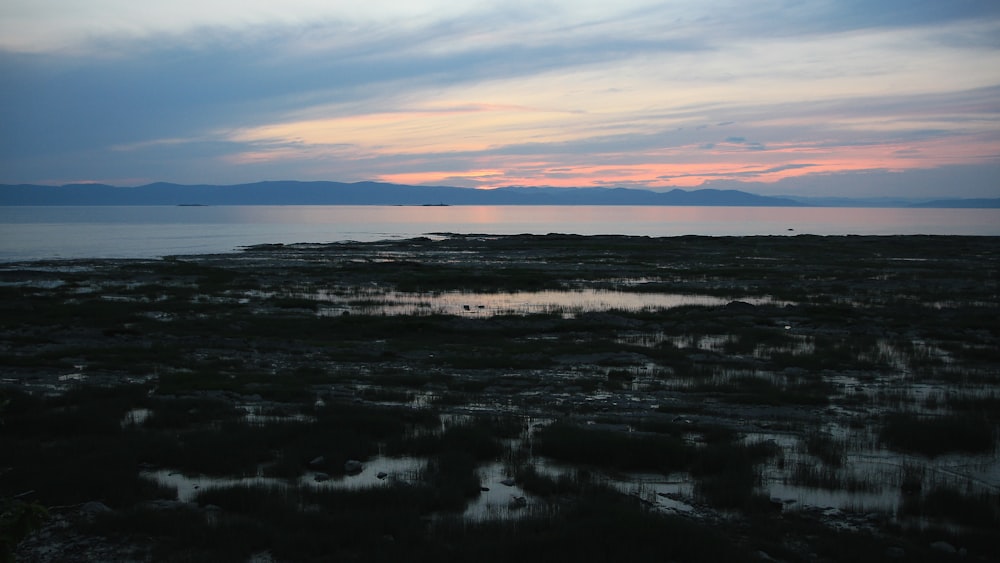 body of water under cloudy sky during sunset