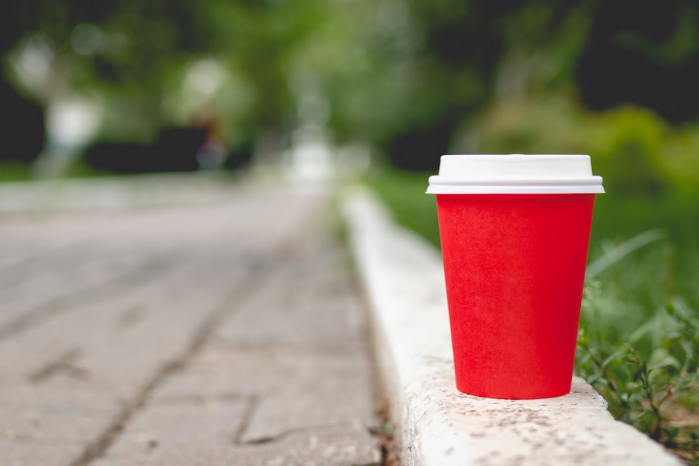 Vaso de plástico rojo y blanco sobre piso de concreto gris