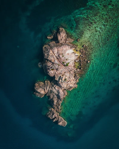 Aerial view of Lobos Island's turquoise waters and rocky coastline under clear blue sky.