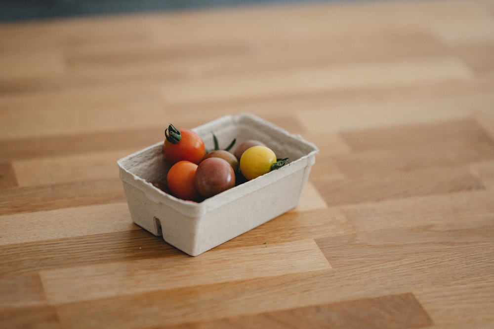 Frutos redondos rojos y amarillos en caja de cartón marrón