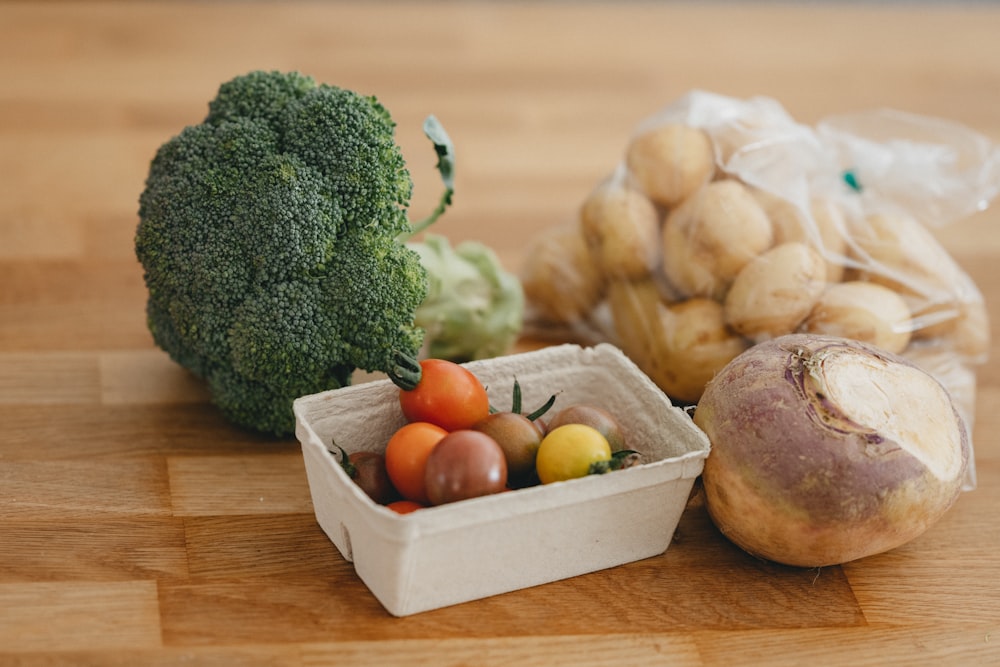 green broccoli and orange fruit on brown wooden tray