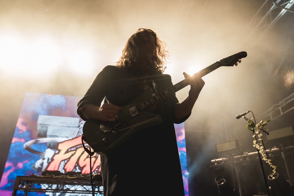 man in black t-shirt playing electric guitar