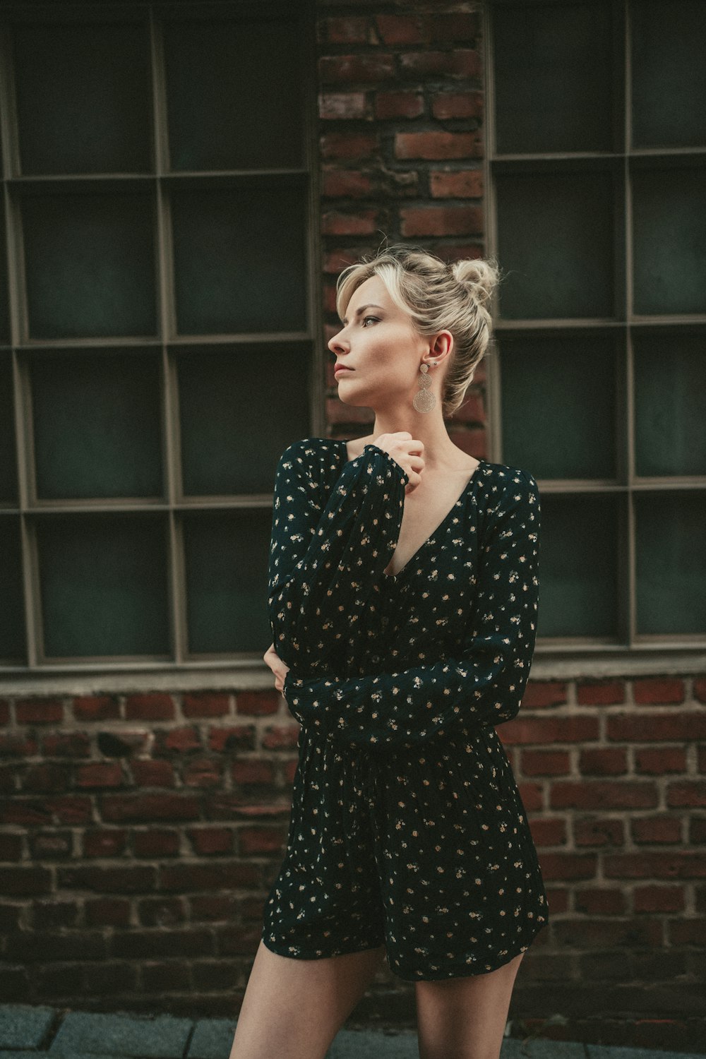 woman in black and white polka dot long sleeve dress standing near brown brick wall