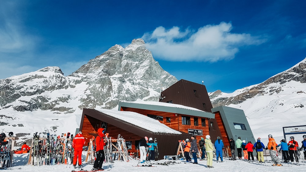 Menschen, die tagsüber auf schneebedecktem Boden in der Nähe eines braunen Holzhauses stehen