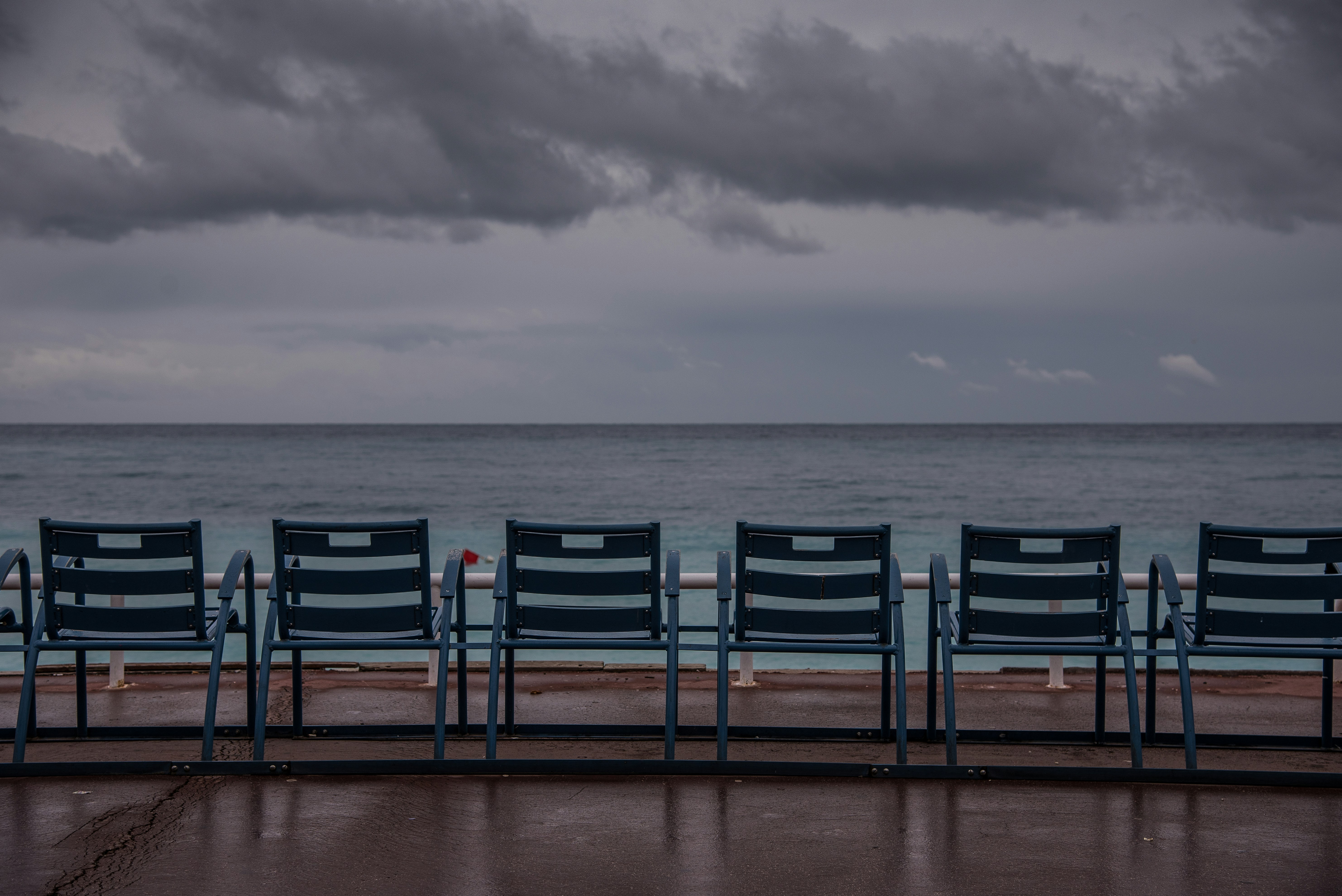 brown wooden chairs on brown sand near sea under white clouds during daytime