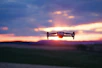 A sleek drone hovering over a vibrant Indian cityscape at sunset.