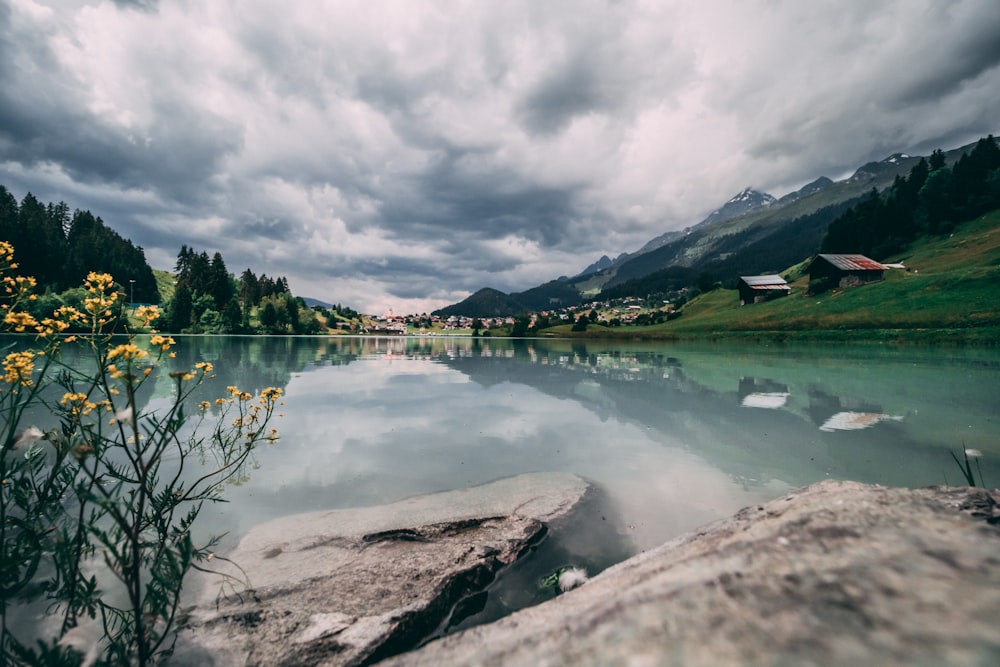 lake near mountain under cloudy sky during daytime