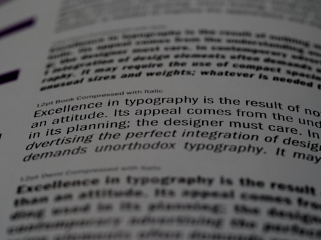 A close-up of a printed page showing text in different fonts and sizes. The visible text discusses typography, mentioning elements like attitude, planning, and the integration of design. The focus is on one sentence and the text around it is blurred.