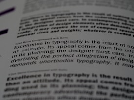 A close-up of a printed page showing text in different fonts and sizes. The visible text discusses typography, mentioning elements like attitude, planning, and the integration of design. The focus is on one sentence and the text around it is blurred.