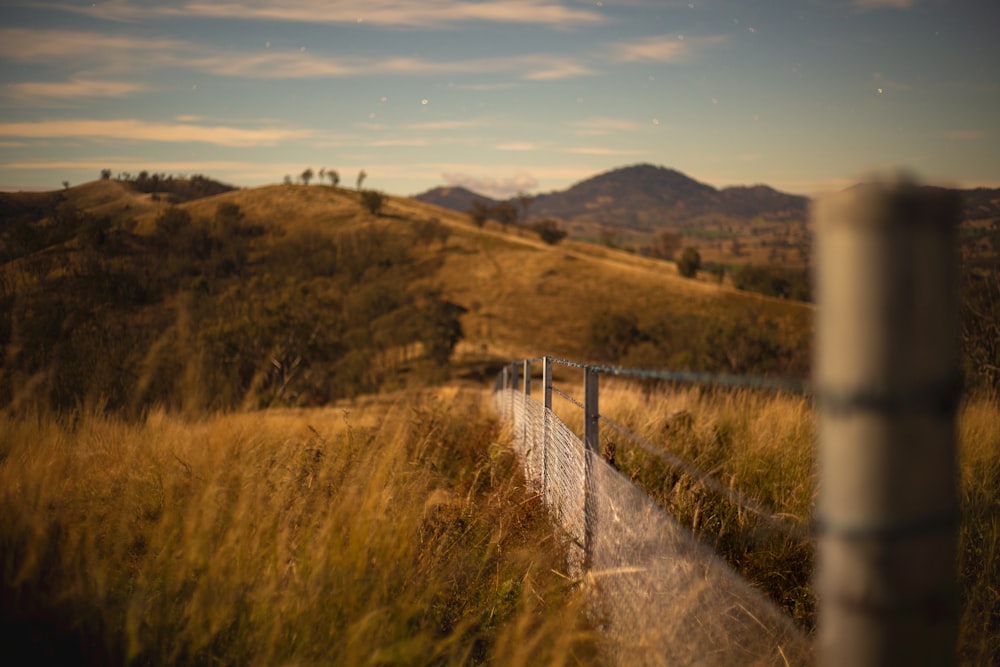 brown grass field near mountain under blue sky during daytime