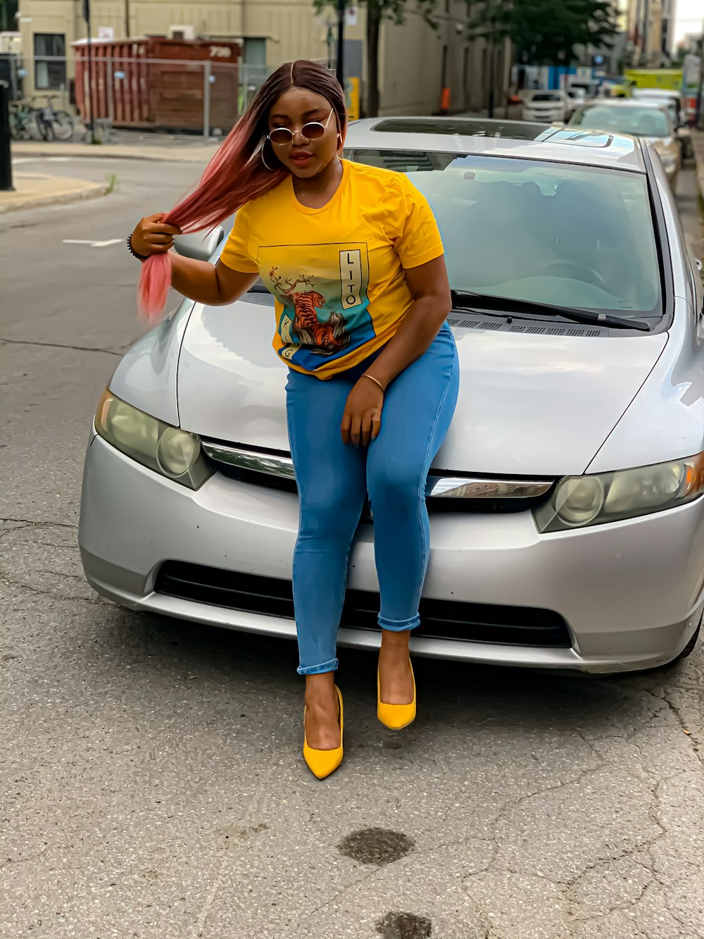 woman in yellow crew neck t-shirt and blue denim jeans standing beside silver car during