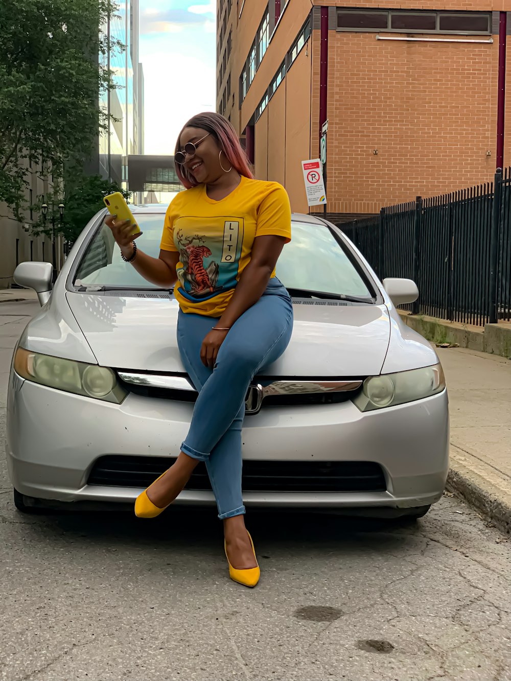 woman in yellow crew neck t-shirt and blue denim jeans leaning on silver car