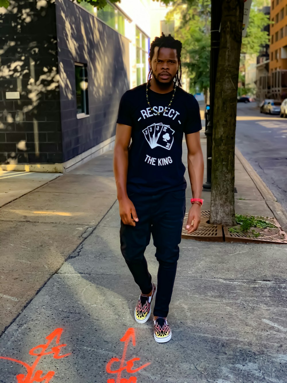 man in black and white crew neck t-shirt and black pants standing on gray concrete