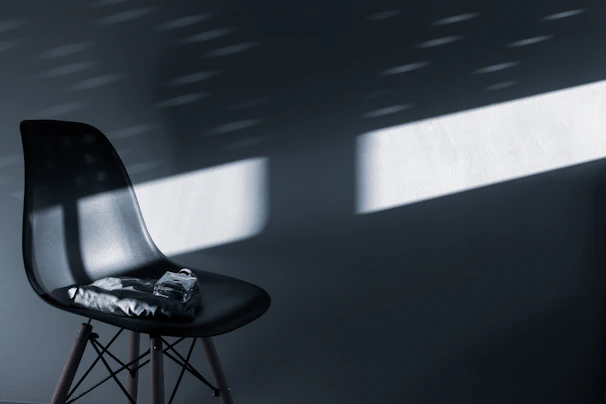 Softly lit scene of a minimalist black and white scarf draped over a sleek chair
