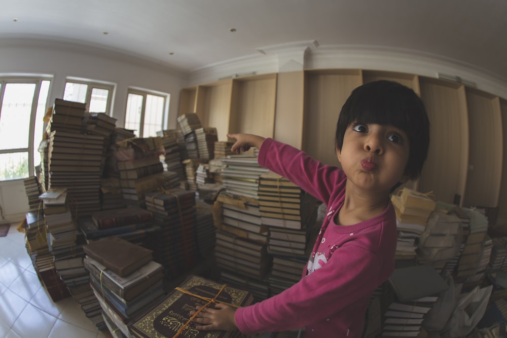 girl in pink long sleeve shirt standing near books