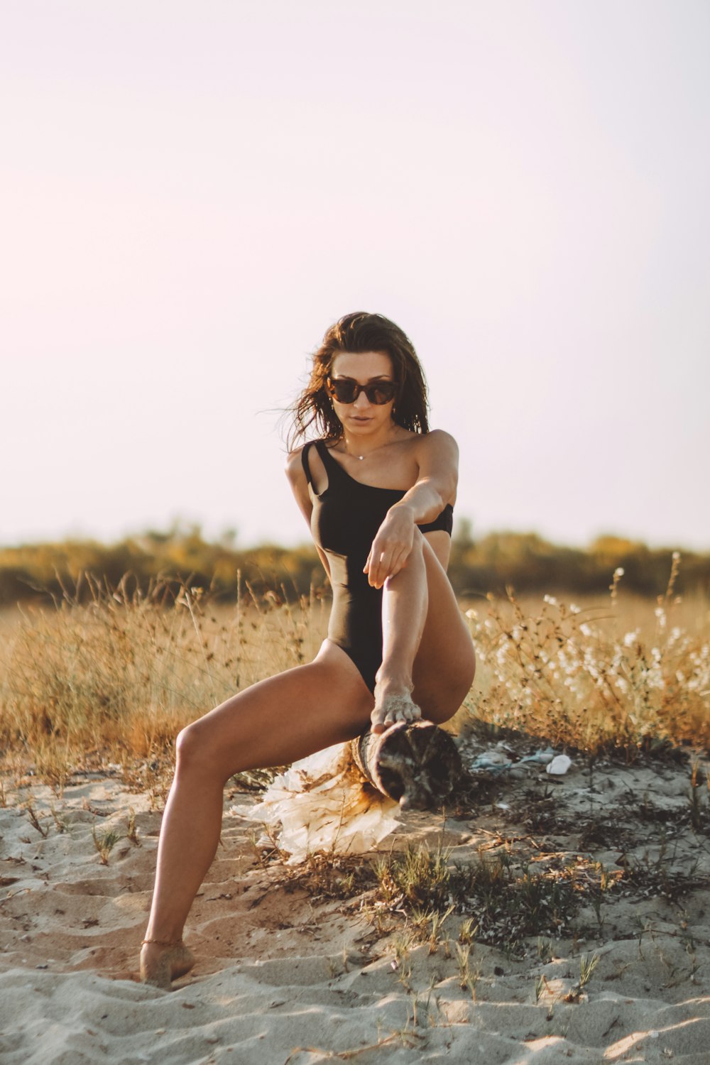 Mujer en bikini negro sentada en roca marrón durante el día