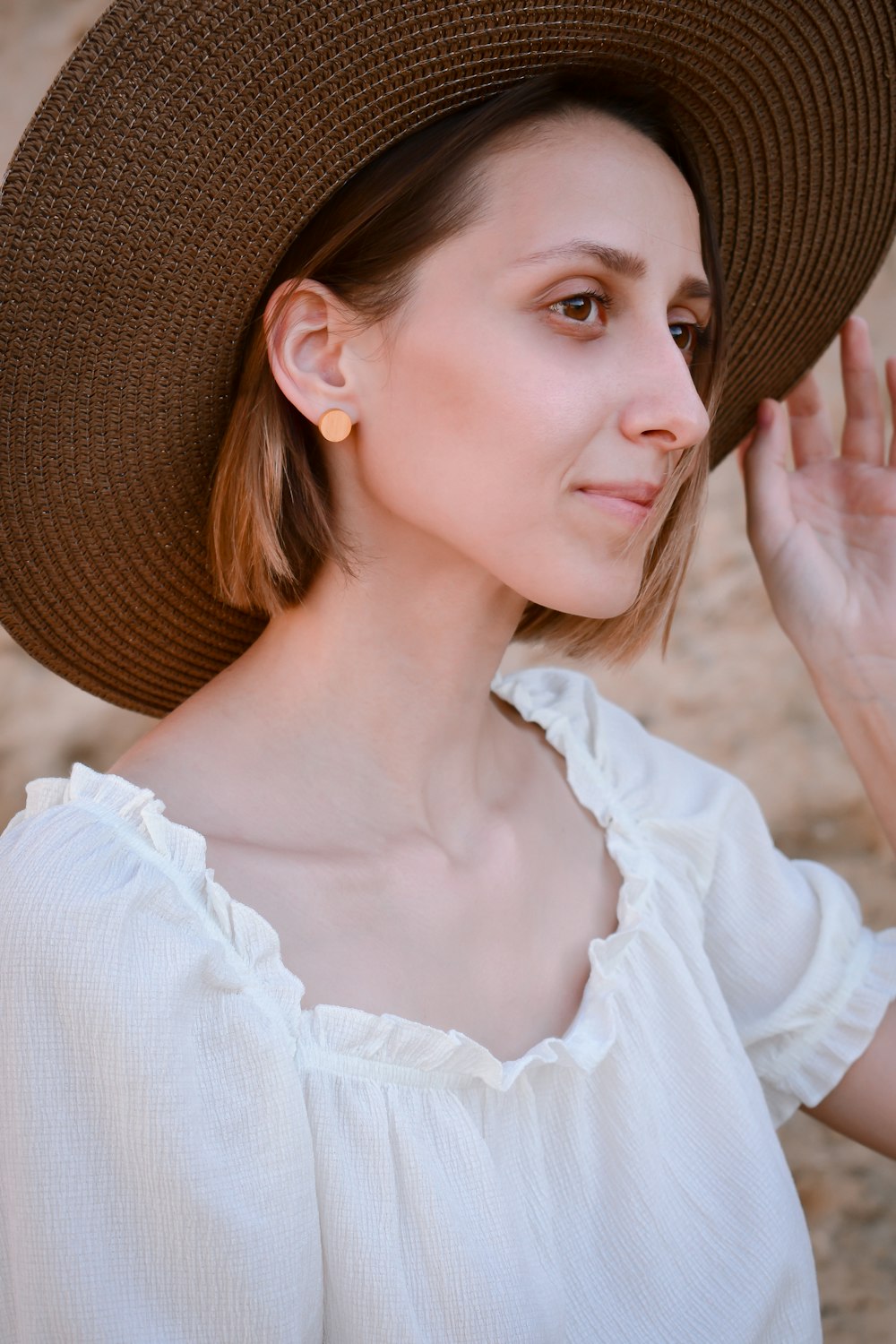 woman in white long sleeve shirt wearing brown hat