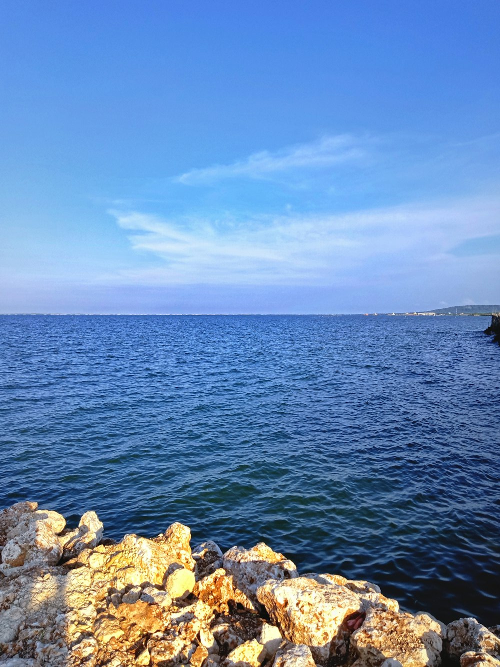 brown rocks beside body of water under blue sky during daytime