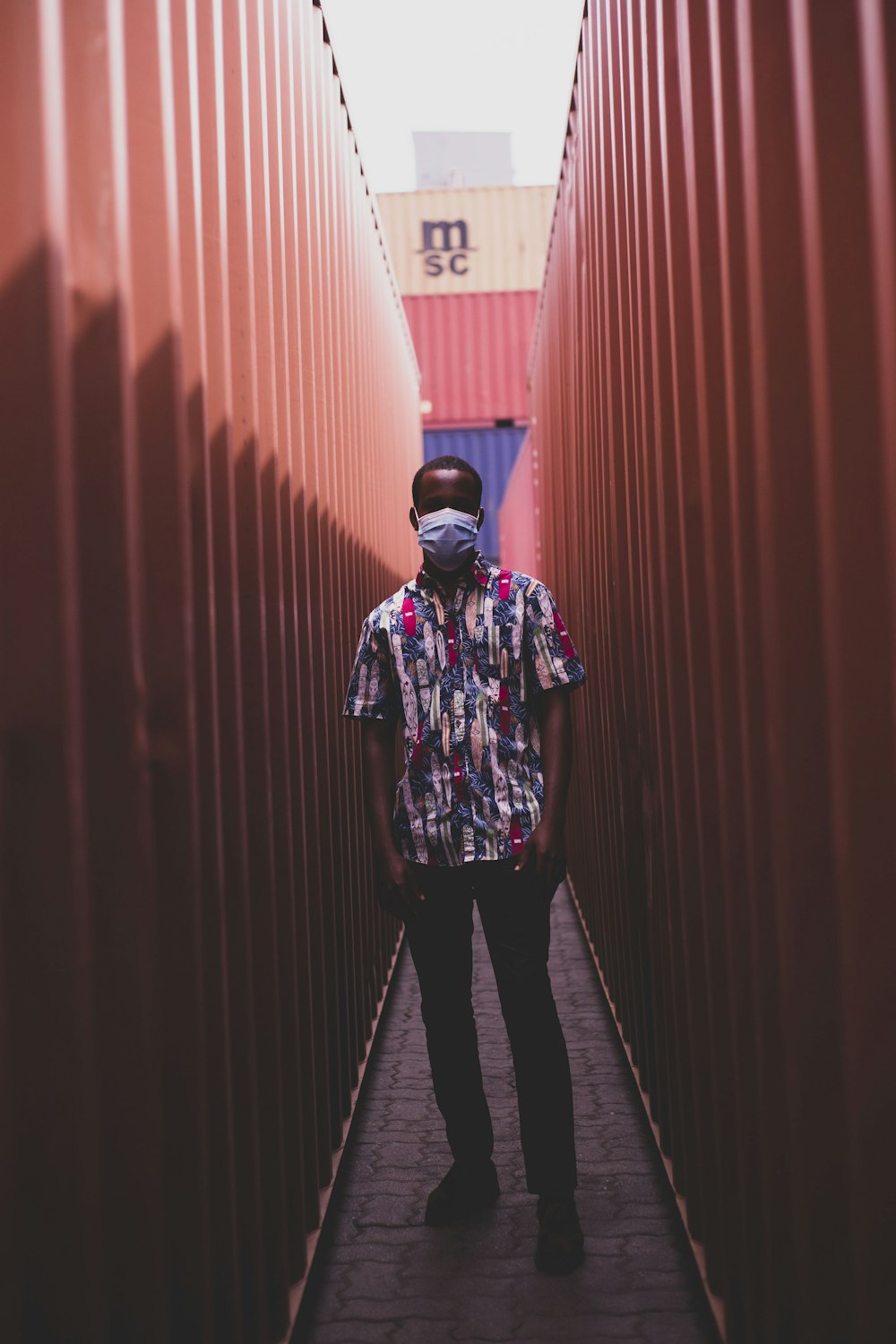 man in black and white floral long sleeve shirt and black pants standing on hallway