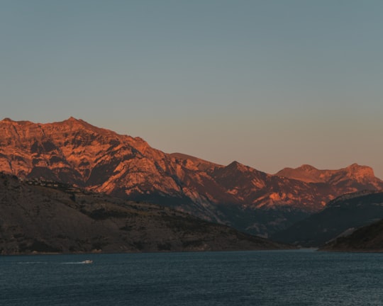 brown mountains near body of water during daytime in Lac de Serre-Ponçon France